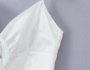 Vue détaillée du haut en satin blanc avec des liens licou et une texture plissée au buste