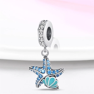 Macro detail of 925 silver ocean charm featuring starfish with blue stones and turquoise shell