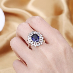 Detailed view of luxury ring with oval blue gemstone and white zircon on golden silk