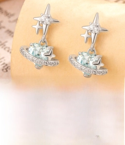 Macro detail of star planet heart earring with blue gemstone and titanium steel screw back