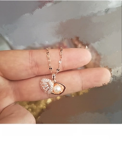 Close-up of shell pearl pendant necklace with sparkling diamonds in rose gold finish