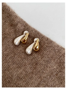 Macro detail of two-tone teardrop earrings in matte silver and glossy gold finish
