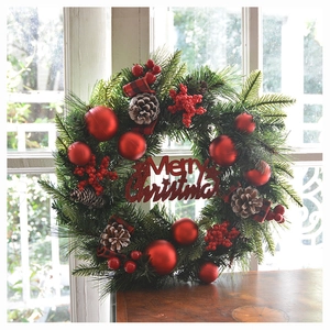 Detailansicht eines Weihnachtskranzes mit roten Beeren, Tannenzapfen und Frohe Weihnachten