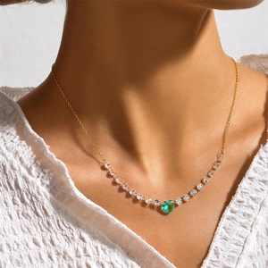 Close-up of a gold necklace featuring a green heart pendant and sparkling clear stones
