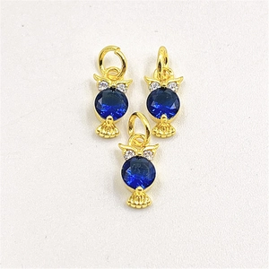 Macro detail of owl pendants with deep blue crystals and gold-plated zircon settings