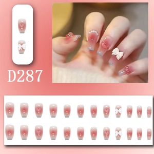 Detail of pink gradient press-on nails with 3D resin bows and pearl embellishments