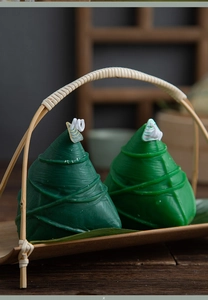 Detail of zongzi-shaped scented candles in a bamboo basket with a warm rustic setting