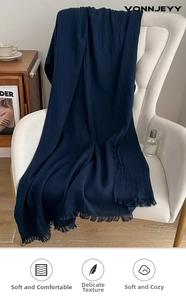 Detail of dark blue meditation shawl with frayed fringe edges on a white armchair