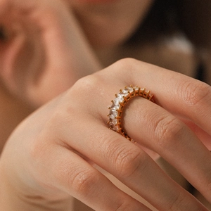 Macro detail of gold-plated eternity ring with square-cut cubic zirconia in claw setting
