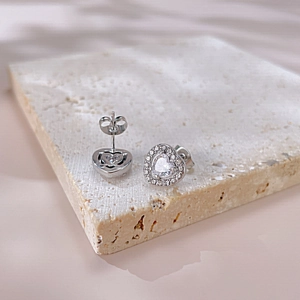 Macro detail of silver heart stud earrings with zircon stones on stone base