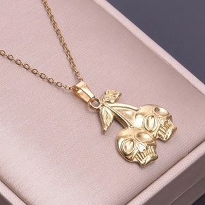 Close-up of gold stainless steel skull cherry pendant with 18k plating on pink box