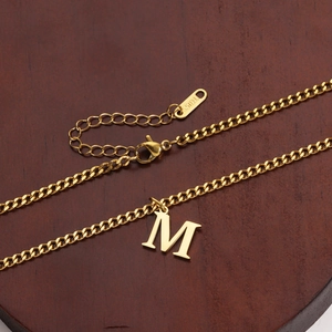 Detail of 18K gold-plated stainless steel M letter pendant with S.STEEL material hallmark