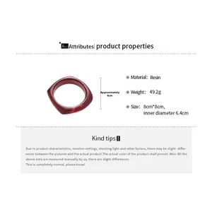 Detail view of a dark red faceted resin bangle showing geometric angles and specifications