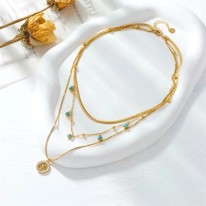 Multi-layer gold tree of life necklace with turquoise beads in elegant white ceramic tray