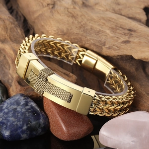Close-up of golden hip hop cross chain bracelet with magnetic clasp on a stone background