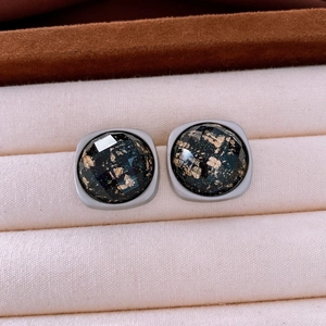 Détail macro de boucles d'oreilles en acrylique avec feuilles d'or et finition métal gris