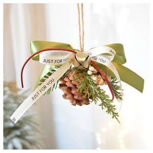 Close-up of handmade pine cone ornament with green spruce sprigs and golden bells