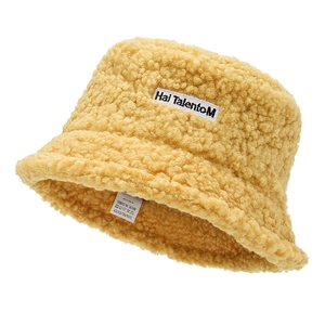 Close-up of yellow fluffy bucket hat showing warm fleece texture and polyester care label