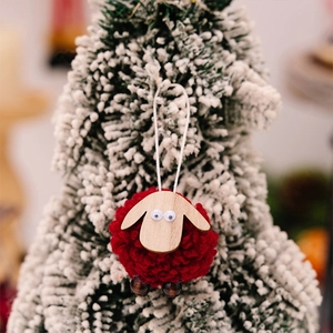 Macro shot of a red wool felt sheep ornament hanging on a festive Christmas tree branch