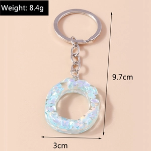 Close-up of resin keychain with blue sequins and dimension labels for weight and size