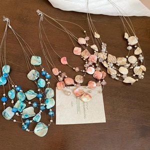 Macro detail of multi-layer beaded necklaces with irregular shell pendants in three colors