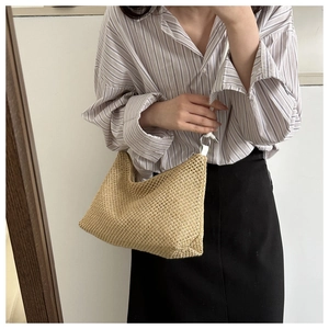 Fashionable beige straw crossbody bag with white leather strap shown on a model