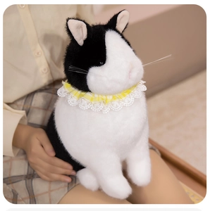 Detail of a fluffy black and white plush cat with a yellow plaid lace collar on knees