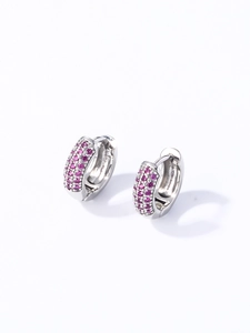 Détail de créoles argentées serties de zircons roses sur fond blanc impeccable