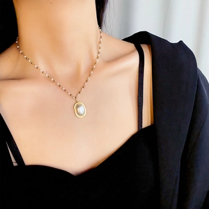 Elegant gold titanium steel necklace featuring a large oval white pearl pendant on model