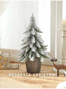 Detailed close-up of a mini flocked Christmas tree in a grey pot for desktop holiday decor