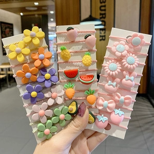 Colorful elastic hair ties with resin fruit and flower charms in a hand-held display