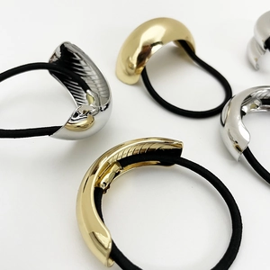 Minimalist elastic hair tie with textured gold and silver arched metal cover