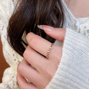 Detail shot of a delicate gold bow ring on finger with soft winter knit background