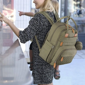 Detail of army green diaper bag with woven texture and leather zipper pull on mother's back