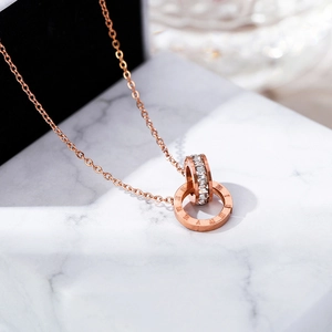 Macro detail of rose gold double ring necklace with Roman numerals and pavé zircons