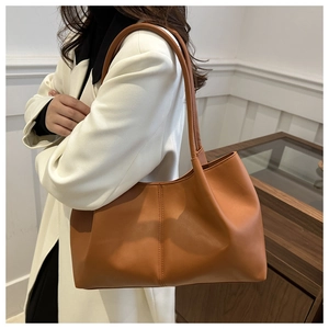Close-up of caramel brown leather tote bag with vertical stitching on a white coat
