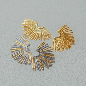 Macro shot of gold and silver sunburst stud earrings with hammered metal texture details
