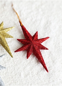 Detailed close-up of a red glittered eight-pointed star ornament for Christmas trees