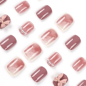 Short red press-on nails with marble texture, 3D bows, and delicate pearl accents