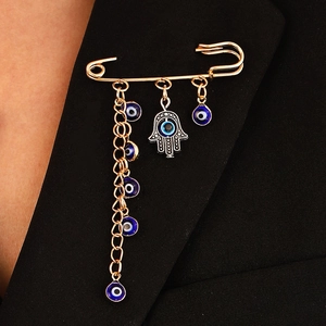 Hamsa Hand and Evil Eye gold chain brooch pinned on a black suit lapel for punk style