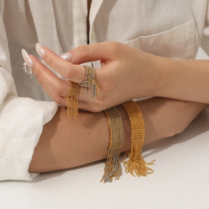 Detail of beaded tassel rings and bracelets in two-tone gold and silver on female model
