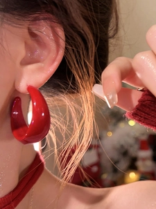 Gros plan de boucles d'oreilles C épaisses en acrylique rouge portées par un modèle