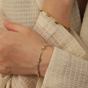 Gold snake bone bracelet with baguette-cut white zircon stones on a beige fabric background
