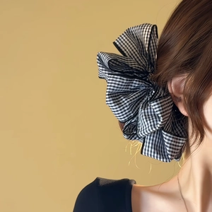 Detail view of large black and white grid fabric bow hair clip on model hair