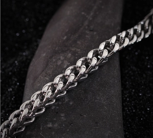 Macro shot of silver stainless steel wolf head link chain bracelet on dark stone texture