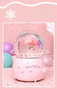 Detail of pink cherry blossom crystal ball with angel figurine and 360-degree rotation feature