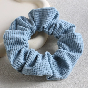 Close-up of blue corduroy scrunchie on white tray with French vintage style texture