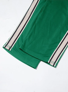 Close-up of green joggers with side stripes showing premium fabric texture and stitching