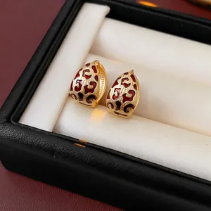 Golden earrings with leopard print enamel presented in a luxury jewelry display box