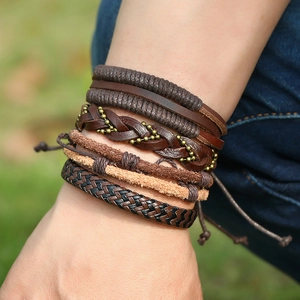 Close-up of layered braided leather bracelets in brown and black with bronze beads